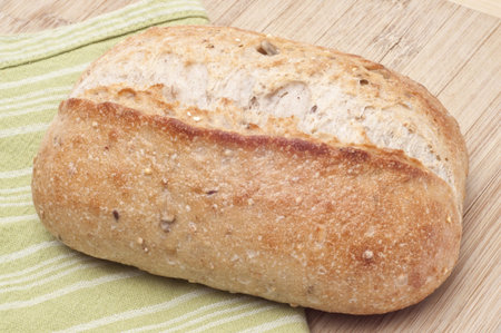 Loaf of Crusty Whole Wheat Bread on Wooden Block.