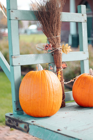 two pumpkins and a broom on the porch of a country houseの写真素材