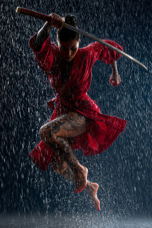 Young beautiful woman in red kimono with sword in the rainの素材