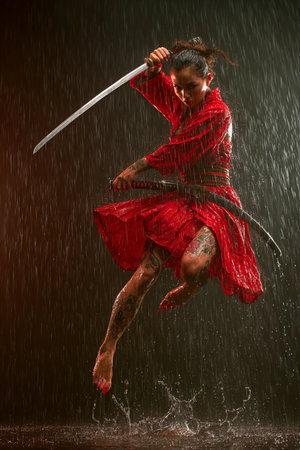 Beautiful young woman in red dress with katana in the rainの素材