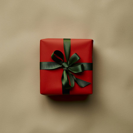 Red gift box with green bow on beige background, top viewの素材