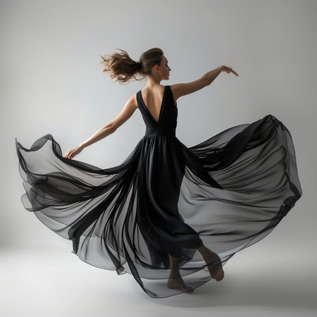 Young beautiful dancer in black dress dancing on gray background. Studio shot.の素材
