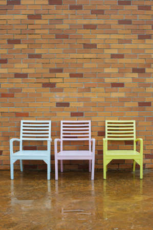 Colorful chairs in a row against brick wallの写真素材