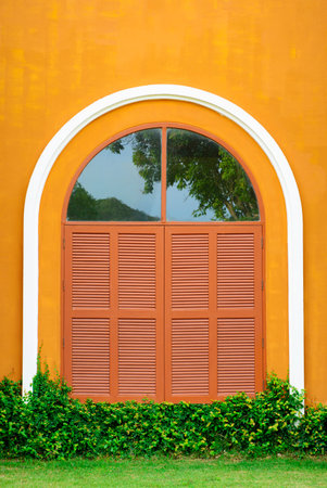 Window shutter of an orange house with grass
