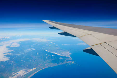Passenger view from airplane flying over ocean and islandの写真素材