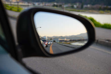 Rear view mirror reflecting a line of cars behindの写真素材