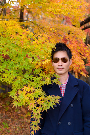 Japanese man with maple leaves in autumn background
