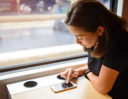 An Asian woman using smart phone while traveling by trainの写真素材