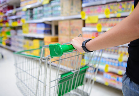 Closeup hand pushing shopping cart in groceries store