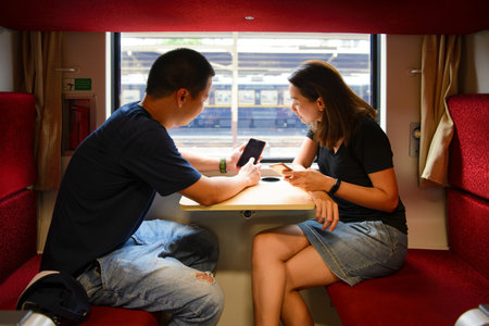 Young tourist man and woman using on the phone on train while travel