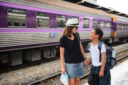 Happy son with mother on platform at a train stationの写真素材