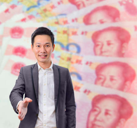Businessman gives a handshake with China banknote background. Business deal or agreement and success concept.の写真素材
