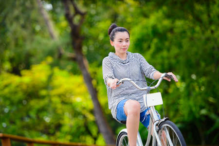 Asian woman riding a vintage bicycle in a parkの写真素材