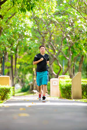 Young man in sports clothing jogging in park with headphoneの写真素材