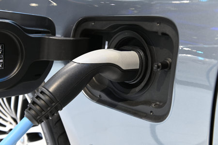 Close up electric car charging process by power cable supply plugged in