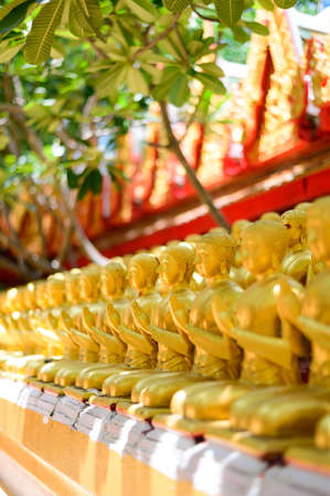 Row of golden buddha statues at templeの写真素材