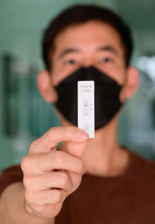 A man holding covid-19 negative test result with antigen rapid test kit (ATK)の写真素材