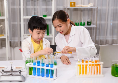 Science teacher testing a chemical experiment with child students in laboratory classroomの写真素材