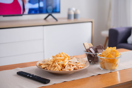 Snack on wooden table with television on background