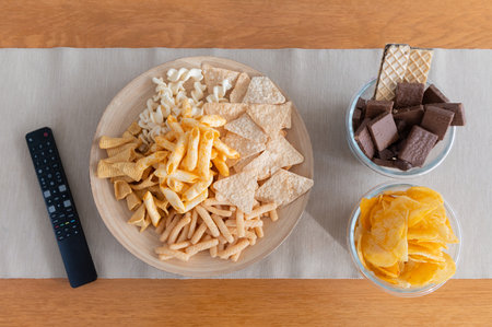 Top view of snack on wooden table and remote controlの写真素材