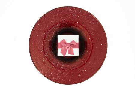 Christmas gift box over an elegant red plateの写真素材