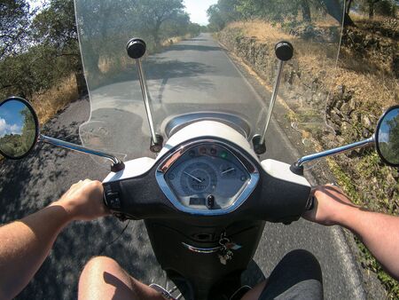 person riding a scooter on a country road, you see your hands holding the handlebars.の写真素材