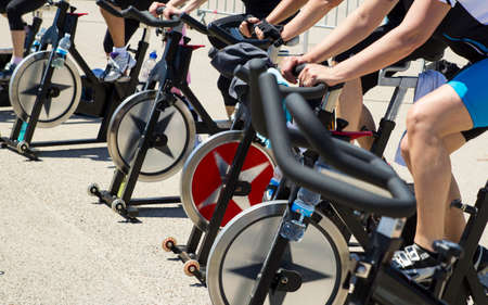 Legs moving during a workout of spinning-----Imperia, IM, Italy - May 18, 2014: People perform a spinning session outdoors in an urban park of liguria. Athlets training an their special bikers to keep healthyのeditorial素材
