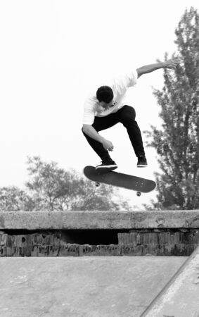 a guy make a jump and backside kickflip with the skateboard.の写真素材