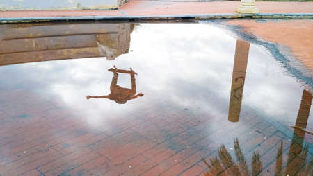 Reflection on the water of a boy jumping on the skateの写真素材