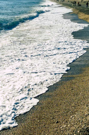 Beautiful beach in Liguria with sea waves, foam and sandの写真素材