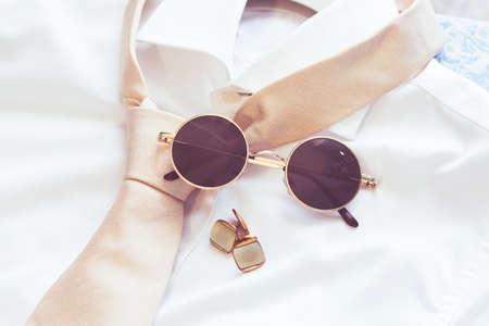 Elegant men's accessories and clothes used for a wedding: sunglasses, white shirt, tie and twinsの写真素材