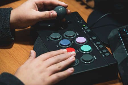 Imperia, Italy, 20/11/2019: Boy who presses the colored button of an arcade pad to play vintage video games, photo of a normal moment of life.の写真素材