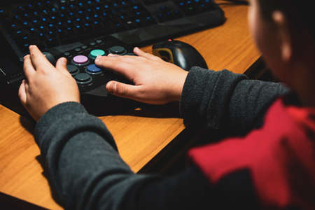 Imperia, Italy, 20/11/2019: Boy who presses the colored button of an arcade pad to play vintage video games, photo of a normal moment of life.の写真素材