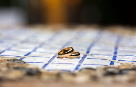 golden wedding rings over a table decorated with colored tilesの写真素材