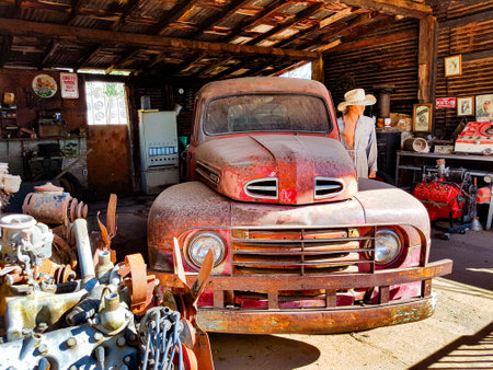 Vintage Ford truck in a rustic garage with retro decor, exposed engines, and a mannequin wearing a white hatの写真素材