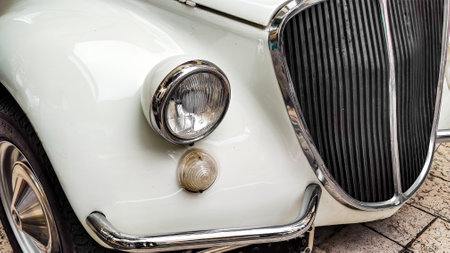 Vintage white car with round headlight and chrome grille, front detailの写真素材