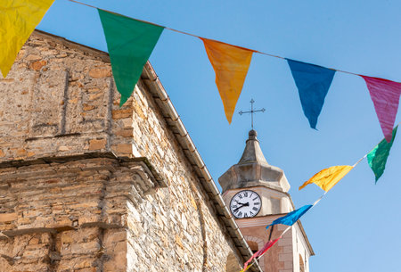 Church Bell Tower with Clock and Colorful Flags in Liguria Italyの写真素材