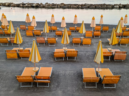 Ligurian Beach with Orange Sunbeds and Umbrellas at Sunsetの写真素材
