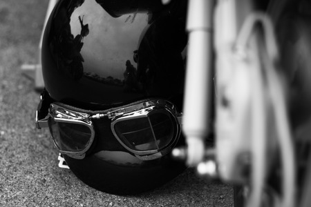 Motorbike helmet and goggles on the ground next to a motorbikeの写真素材