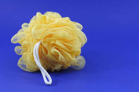yellow body sponge with white string on a blue background.の写真素材
