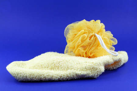 yellow body sponge and wash cloth on blue background.の写真素材