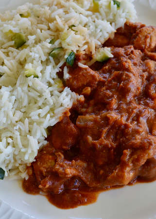 Butter chicken and rice on a white plateの写真素材