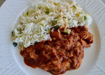 Butter chicken and rice on a white plateの写真素材