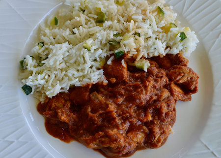 Butter chicken and rice on a white plateの写真素材