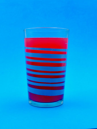 Cocktail glass with red and blue stripes on a blue backgroundの写真素材