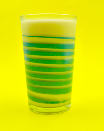 Glass of green and yellow color on a yellow background with copy spaceの写真素材