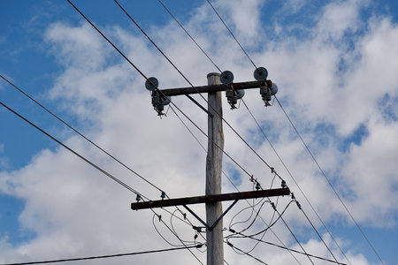 Power lines against the blue sky with white clouds. Electricity post.の写真素材