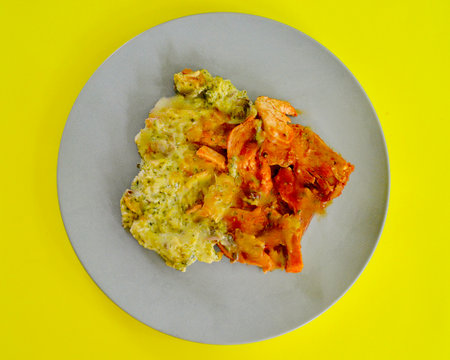 Plate of smokey bbq chicken with creamy broccoli on yellow backgroundの写真素材
