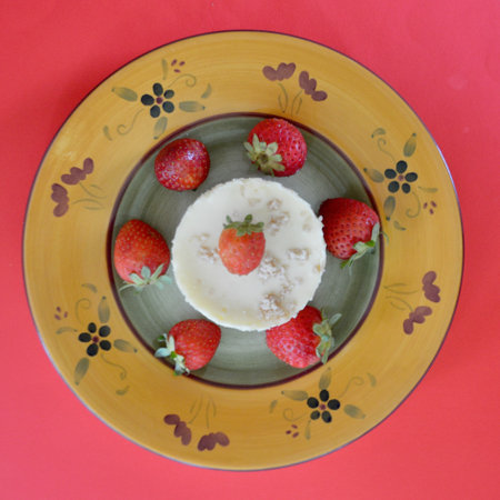 Cheesecake with fresh strawberries on a colorful plate on a red backgroundの写真素材