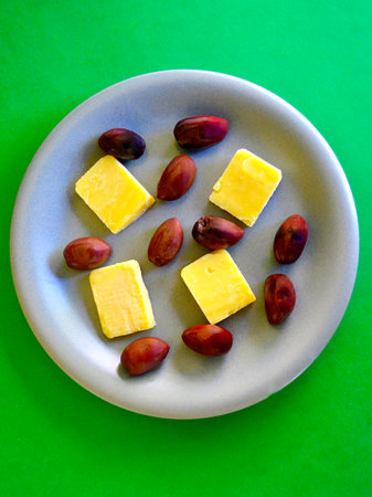 Pieces of cheese and kalamata olives on a plate on a green backgroundの写真素材